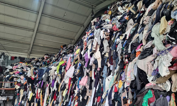창고에 거대하게 쌓여 있는 의류 폐기물 더미